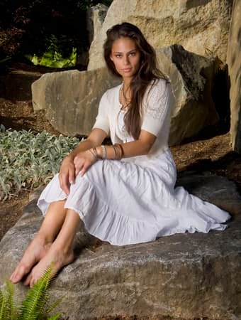 a young woman in a white dress is posing outdoors