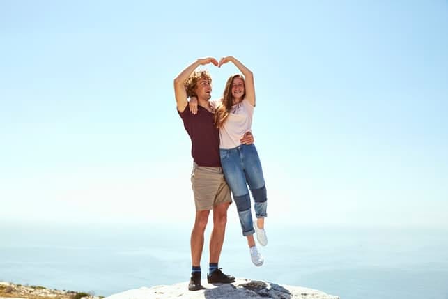 a happy young couple making a heart sign with their hands