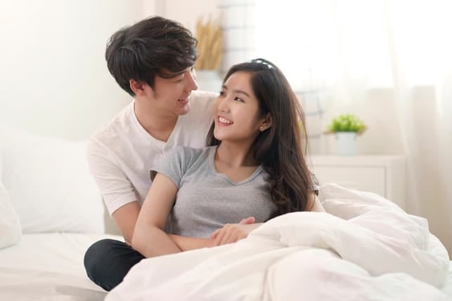 an Asian couple cuddling and looking in each other’s eyes