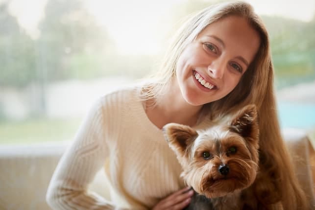 a blonde girl with a dog posing and smiling