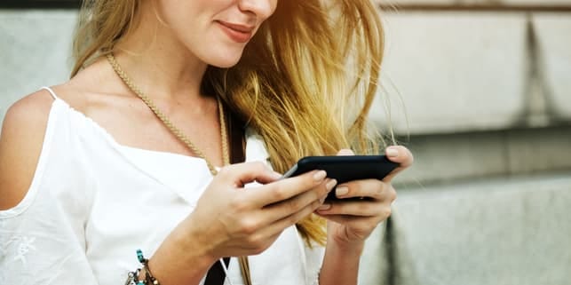a woman is using her smartphone while smiling