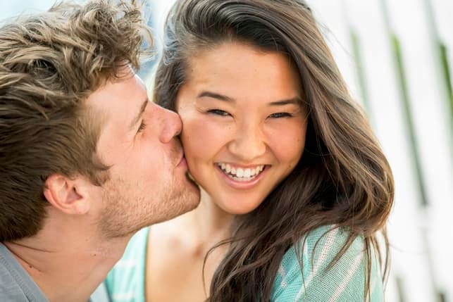 a man kissing his girlfriend’s cheek