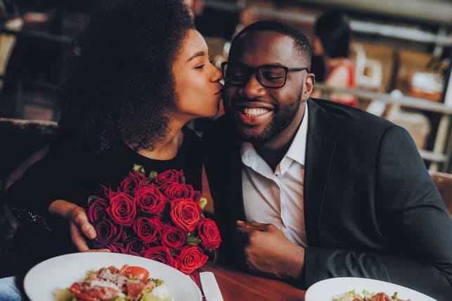 a woman with flowers is kissing her boyfriend