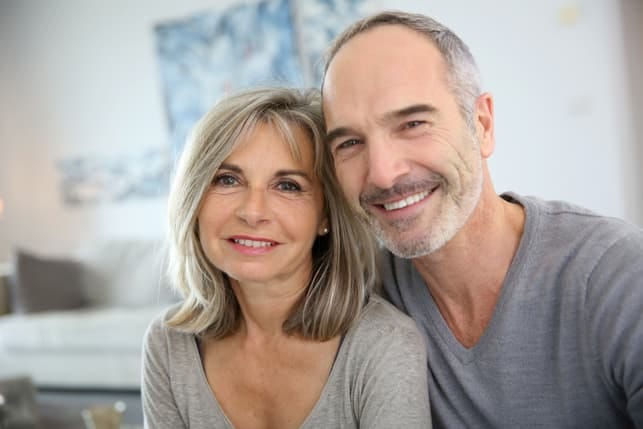 a mature couple hugging and smiling while posing at home