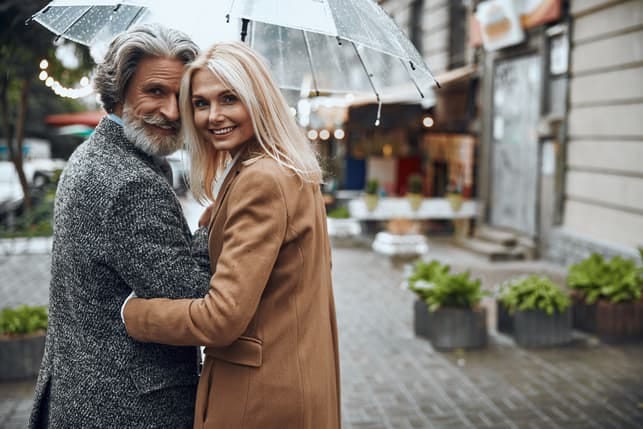a beautiful mature couple having a date and walking together under an umbrella