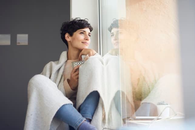a portrait of a beautiful mature woman sitting next to a window