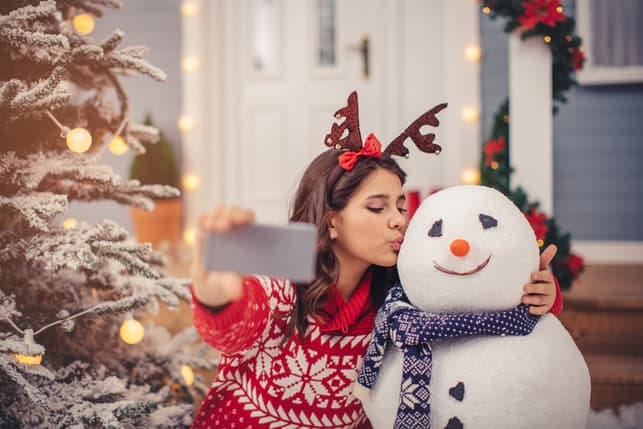 a girl taking a selfie and kissing a snowman