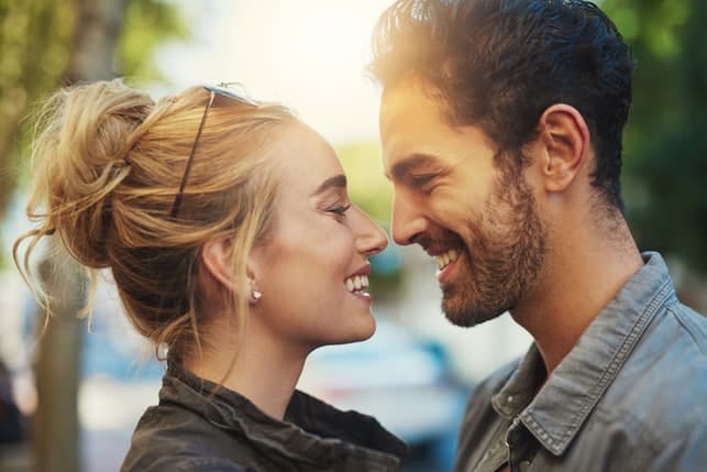 a couple is looking at each other and smiling outdoors