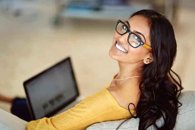 an indian woman with a laptop smiling