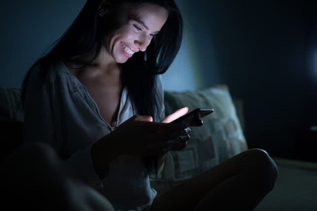 a happy woman is reading her messages via her smartphone