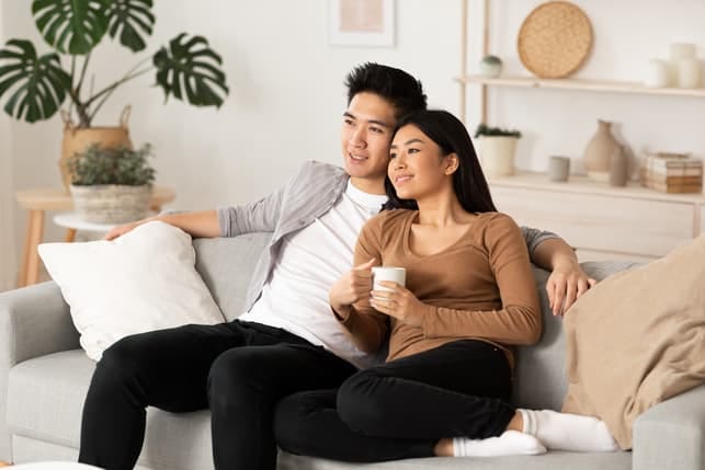 a happy Asian couple are relaxing at home while thinking about their future
