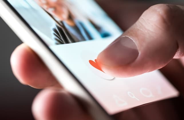 a hand of a man using a dating app on his smartphone