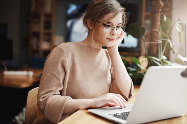a young girl using her laptop and daydreaming