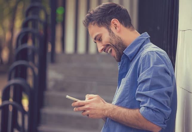 a happy man is using his smartphone