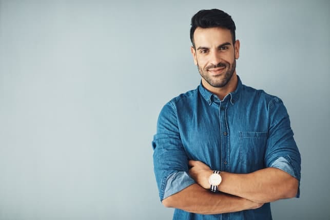 an attractive man in a blue shirt posing