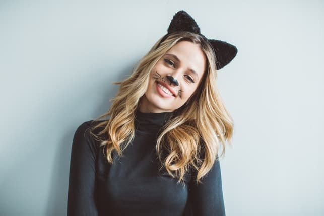 a happy woman with cat make-up having fun