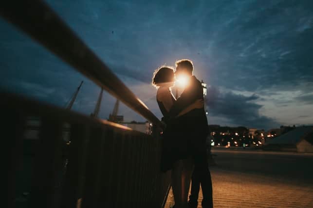 a couple kissing outside romantically in the evening