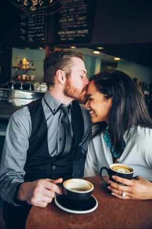 a mixed couple is kissing in a cafe